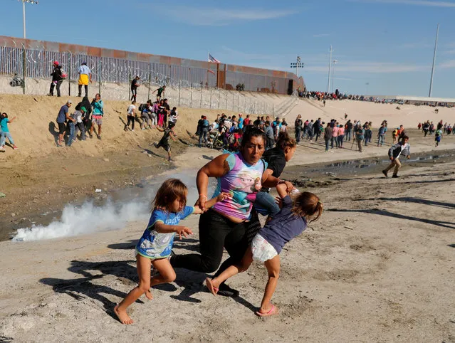 Maria Meza (C), a 40-year-old migrant woman from Honduras, part of a caravan of thousands from Central America trying to reach the United States, runs away from tear gas with her 5-year-old twin daughters Saira Mejia Meza (L) and Cheili Mejia Meza (R) in front of the border wall between the U.S. and Mexico, in Tijuana, Mexico, November 25, 2018. (Photo by Kim Kyung-Hoon/Reuters)