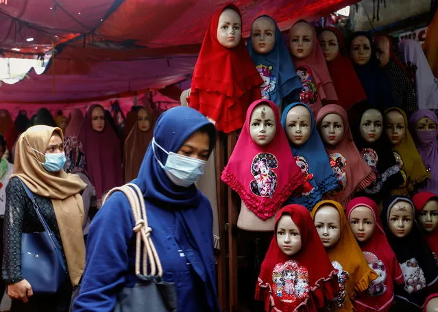 Women walk past hijabs displayed for sale at the Tanah Abang textile market in Jakarta, Indonesia, March 16, 2021. (Photo by Ajeng Dinar Ulfiana/Reuters)