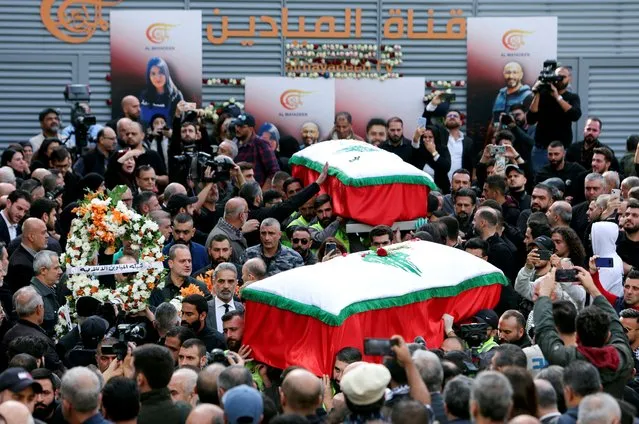 Mourners stand near the coffins of the two journalists working for Lebanon-based Al Mayadeen TV channel said to be killed by an Israeli strike on Tuesday in southern Lebanon, as they gather outside the channel's building to offer prayers ahead of their funeral, in Beirut, Lebanon on November 22, 2023. (Photo by Aziz Taher/Reuters)