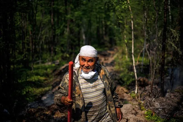 Ivan Fyodorov, 65, helps firefighters to control a five-kilometre long trench – that they dug with a tractor some days earlier – to prevent a wildfire from reaching their land in the Siberian region of Yakutia, at the edge of the village of Byas-Kyuel, on July 26, 2021. Fuelled by a June heatwave, wildfires have swept through more than 1.5 million hectares of Yakutia's swampy coniferous taiga with more than a month still to go in Siberia's annual fire season. It is the third straight year that Russia's coldest region – with a border on the Arctic ocean – has seen wildfires so vicious that they have nearly overwhelmed its Aerial Forest Protection Service. (Photo by Dimitar Dilkoff/AFP Photo)