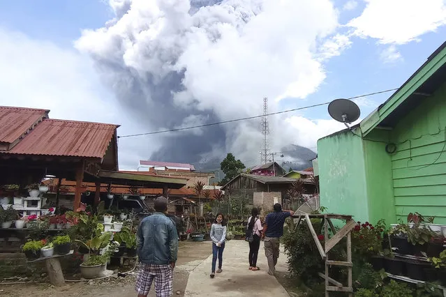 People watch as Mount Sinabung spews volcanic materials during an eruption in Karo, North Sumatra, Indonesia. Wednesday, July 28, 2021. The rumbling volcano on Indonesia’s Sumatra island on Wednesday shot billowing columns of ash and hot clouds down its slopes. (Photo by Sastrawan Ginting/AP Photo)