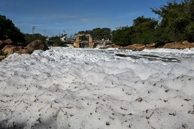 View of the Tiete river covered with toxic foam in Salto, 100km from Sao Paulo, Brazil on July 7, 2023. The Tiete River is 1,100 km long, crossing the state of Sao Paulo, and during the dry season, the sewage that is dumped into the river in the metropolitan region of Sao Paulo forms a toxic foam composed of phosphates and phosphorus present in biodegradable household products such as soap, detergent, soap, toothpaste and shampoo, causing pollution. (Photo by Nelson Almeida/AFP Photo)