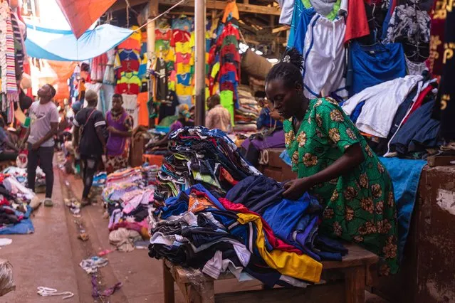 A woman selling second-hand clothes arranges several items at her stall while waiting for costumers in Owino, Kampala's largest second-hand clothes market, on October 7, 2023. Ugandan President Yoweri Museveni announced a ban on the importation of used clothing into Uganda to be effective from September, claiming it affects the development of the local textile industries and stating that used clothes belonged to dead people. Uganda has traditionally imported large quantities of used clothing, which many Ugandans prefer due to its affordability. (Photo by Badru Katumba/AFP Photo)