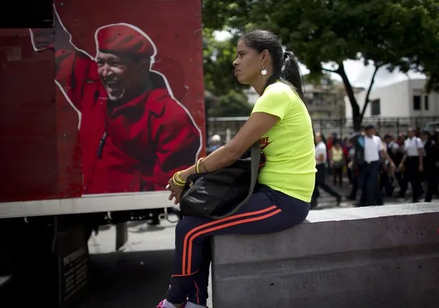 A supporter of Venezuela's President Nicolas Maduro sits next to an image depicting the late president Hugo Chavez during an “anti-intervention” march coinciding with the anniversary of the deadly 1989 social uprising against neoliberal measures known as the Caracazo, in Caracas, Venezuela, Wednesday, February 27, 2019. (Photo by Ariana Cubillos/AP Photo)
