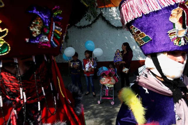 A woman and children carru dressed-up dolls representing baby Jesus between Chinelo costumed dancers during the Feast of Candelaria celebration, where elaborate effigies of young Jesus are carried to be blessed 40 days after his birth, in Xochimilco neighborhood in Mexico City, Mexico, February 2, 2017. (Photo by Carlos Jasso/Reuters)
