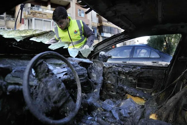 A Hezbollah Civil defense worker searches for body remains on a burned car, near an apartment building where an apparent Israeli strike Tuesday killed top Hamas political leader Saleh Arouri, in the southern suburb of Beirut that is a Hezbollah stronghold, Lebanon, Wednesday, January 3, 2024. The apparent Israeli strike that killed Hamas' No. 2 political leader, marking a potentially significant escalation of Israel's war against the militant group and heightening the risk of a wider Middle East conflict. (Photo by Hussein Malla/AP Photo)