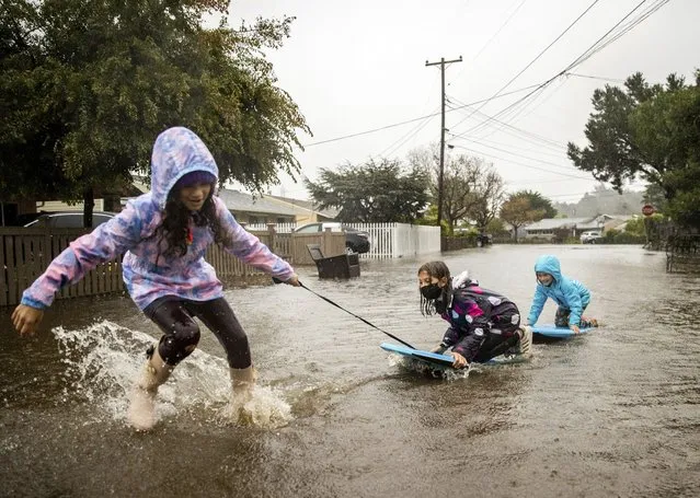 Children play in floodwaters on Robin Road in Mill Valley, Calif., on Sunday, October 24, 2021. (Photo by Ethan Swope/AP Photo)