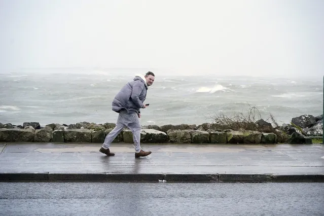 A man walking in high winds at Salthill, Ireland, Sunday, January 21, 2024, during Storm Isha. A Status Red wind warning has been issued for counties Donegal, Galway and Mayo as authorities warn people to take care ahead of Storm Isha's arrival. (Photo by Niall Carson/PA Wire via AP Photo)