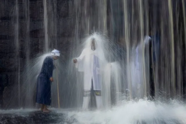 Pilgrims stand under a waterfall as they cleanse themselves of evil spirits during a Sunday morning ritual at a waterfall on the Braamfontein Spruit river in Johannesburg, South Africa, 03 March 2024. The waterfall is used mostly on weekends as the pilgrims come to cleanse themselves in an age old tradition. South Africa religion is often based on tribal values and uses Shamanic roots as its core value system. (Photo by Kim Ludbrook/EPA/EFE)