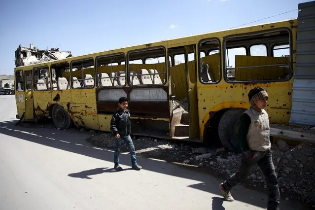 Boys walk past a damaged bus in the rebel-held Qaboun neighborhood of Damascus, Syria March 14, 2016. (Photo by Bassam Khabieh/Reuters)
