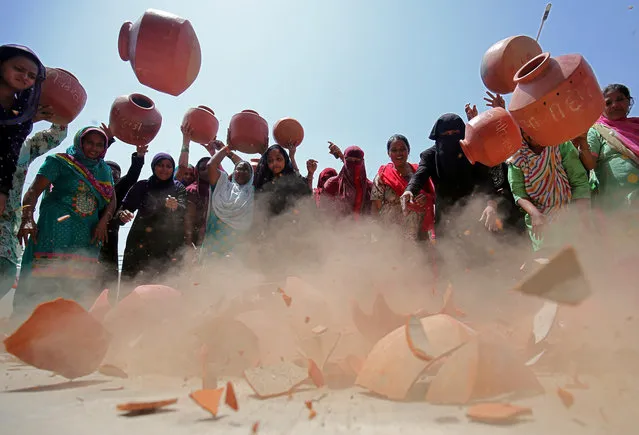 Women throw earthen pitchers onto the ground in protest against the shortage of drinking water outside the municipal corporation office in Ahmedabad, India, May 16, 2019. (Photo by Amit Dave/Reuters)