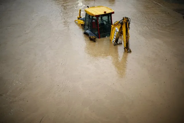 A bulldozer partially covered with water is seen on a flooded street in Santiago, April 17, 2016. (Photo by Ivan Alvarado/Reuters)