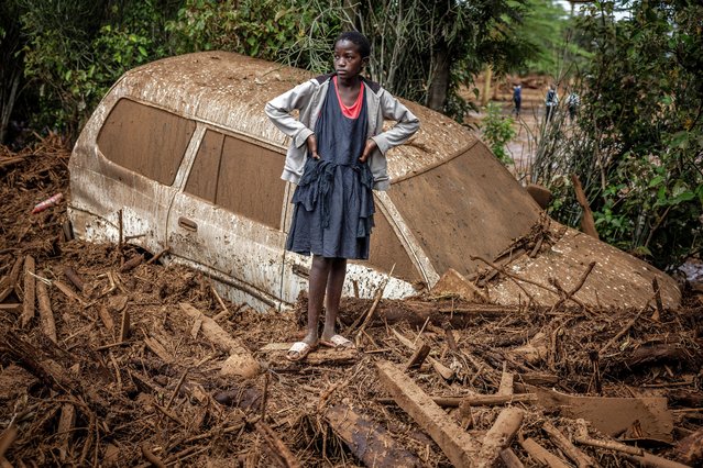 A girl looks on next to a damaged car buried in mud in an area heavily affected by torrential rains and flash floods in the village of Kamuchiri, near Mai Mahiu, on April 29, 2024. At least 45 people died when a dam burst its banks near a town in Kenya's Rift Valley, police said on April 29, 2024, as torrential rains and floods battered the country The disaster raises the total death toll over the March-May wet season in Kenya to more than 120 as heavier than usual rainfall pounds East Africa, compounded by the El Nino weather pattern. (Photo by Luis Tato/AFP Photo)