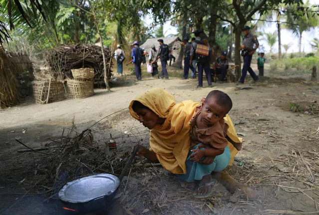 A Rohingya woman carrying her baby cooks her meal  in a Rohingya village, during the national census in Sittwe March 31, 2014. The government on Sunday embarked on its first national census in more than 30 years. (Photo by Soe Zeya Tun/Reuters)