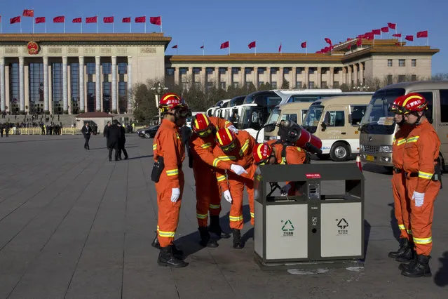 Fire fighters spray chemical water into a bin to put out what appeared to be smoldering caused by cigarette butt near the Great Hall of the People where a plenary session of the National People's Congress is held in Beijing, China, Sunday, March 12, 2017. (Photo by Ng Han Guan/AP Photo)