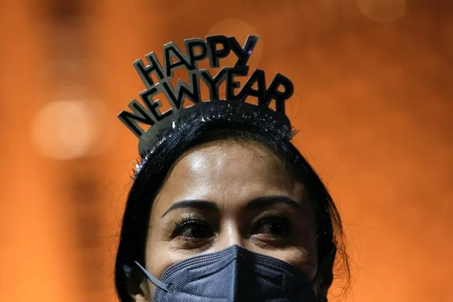 A woman, wearing a protective face mask and a headband, looks on at the Bundaran Hotel Indonesia roundabout where people usually celebrate on New Year's Eve in Jakarta, Indonesia, December 31, 2021. (Photo by Willy Kurniawan/Reuters)