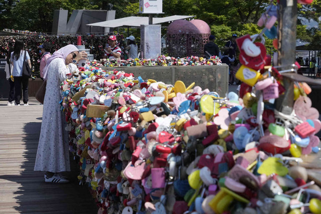 A woman takes photos of “locks of love” hanging on the wall of a terrace of Seoul Tower on Namsan Mountain in Seoul, South Korea, Wednesday, May 29, 2024. Young couples hang their “locks of love” and throw the key away in the hope for eternal love. (Photo by Ahn Young-joon/AP Photo)