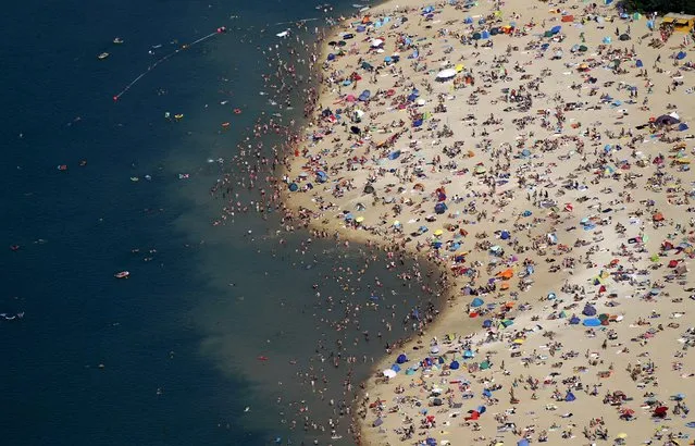 An aerial view shows people at a beach on the shores of the Silbersee lake on a hot summer day in Haltern, Germany, July 4, 2015. A widespread, long-lasting heatwave will affect much of France, Britain, Belgium, the Netherlands and western Germany. (Photo by Ina Fassbender/Reuters)