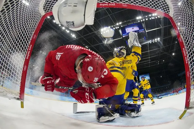 Russian Olympic Committee's Pavel Karnaukhov (15) collides with Sweden goalkeeper Lars Johansson (31) during a men's semifinal hockey game at the 2022 Winter Olympics, Friday, February 18, 2022, in Beijing. (Photo by Matt Slocum/AP Photo)