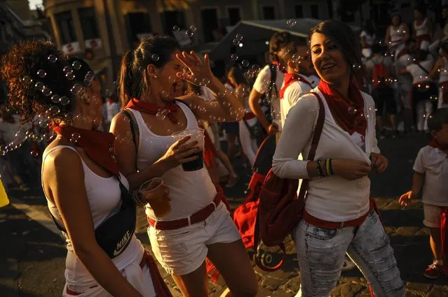 A group of revelers shaking soap bubbles as they enjoy the day  at the San Fermin Festival, in Pamplona, Spain, Saturday, July 11, 2015. Revelers from around the world arrive to Pamplona every year to take part during the eight days of the running of the bulls. (Photo by Alvaro Barrientos/AP Photo)