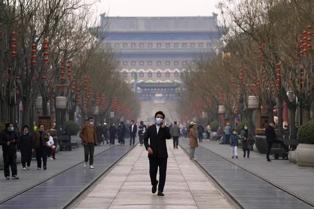 A man wearing a mask walks down the Qianmen Ave retail street on Thursday, March 10, 2022, in Beijing. China is tackling a COVID-19 spike with selective lockdowns and other measures that appear to slightly ease its draconian “zero tolerance” strategy. (Photo by Ng Han Guan/AP Photo)