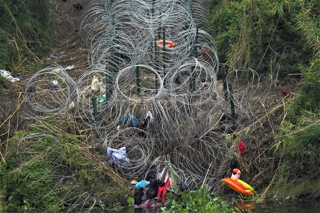 Razor wire and items left behind by migrants cover the U.S. side of the Rio Grande river, empty of migrants swimming across the river the morning after U.S. pandemic-related asylum restrictions called Title 42 were lifted, seen from Matamoros, Mexico, Friday, May 12, 2023. (Photo by Fernando Llano/AP Photo)