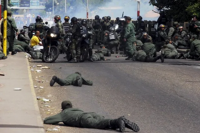 Venezuela's National Guards lie down on floor as they cover themselves during clashes with protesters at Simon Bolivar international bridge, on the border with Colombia, at San Antonio in Tachira state, Venezuela July 29, 2015. (Photo by Reuters/Stringer)
