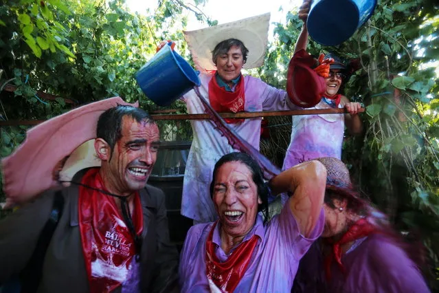 A reveler pours wine on people as they take part in the “Battle of Wine” (La batalla del vino de Haro), a wine fight, during the Haro Wine Festival, in Haro, in the northern province of La Rioja on June 29, 2014. More than nine thousand locals and tourists threw around 130.000 litres of wine at each other during the Haro Wine Festival, according to local media. (Photo by Cesar Manso/AFP Photo)
