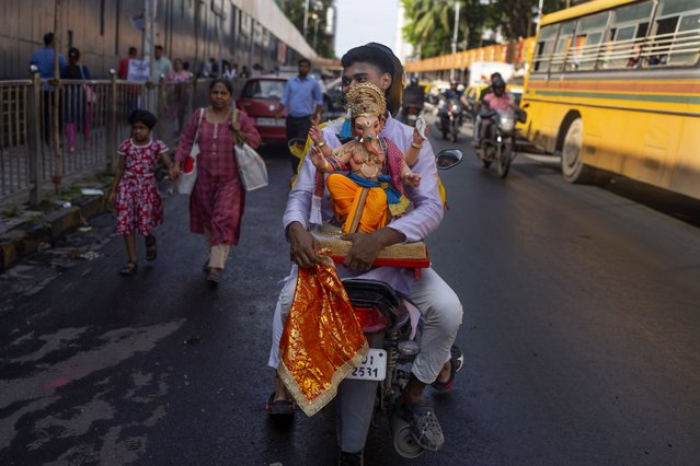 A devotee carries an idol of elephant-headed Hindu god Ganesha to home on a motorcycle for worship during Ganesh Chaturthi festival celebrations in Mumbai, India, Saturday, September 7, 2024. (Photo by Rafiq Maqbool/AP Photo)