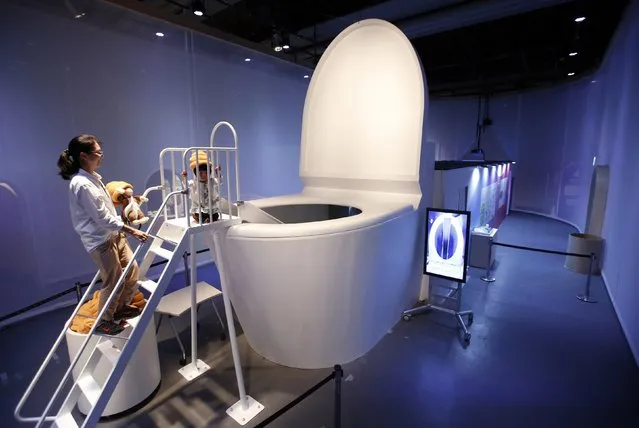 A girl wearing a faeces-shaped hat prepares to slide down into a five-metre (16.4-ft) toilet at an exhibition titled “Toilet!? Human Waste and Earth's Future” at the Miraikan National Museum of Emerging Science and Innovation in Tokyo July 3, 2014. (Photo by Issei Kato/Reuters)