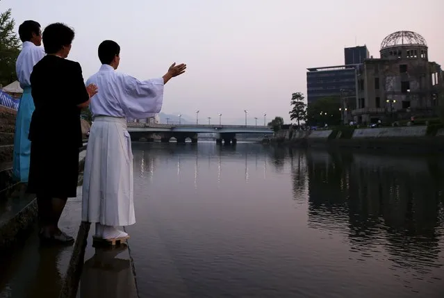 Shinto priests pray at the Motoyasu River opposite the Atomic Bomb Dome at sunrise in Hiroshima, western Japan, August 6, 2015. (Photo by Thomas Peter/Reuters)