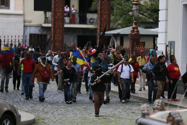Dozens of government supporters set up a picket outside the National Assembly, heckling lawmakers during a special session coinciding with Venezuela’s independence day, in Caracas, Wednesday, July 5, 2017. Wielding wooden sticks and metal bars the group eventually stormed congress and began attacking opposition lawmakers. (Photo by Fernando Llano/AP Photo)