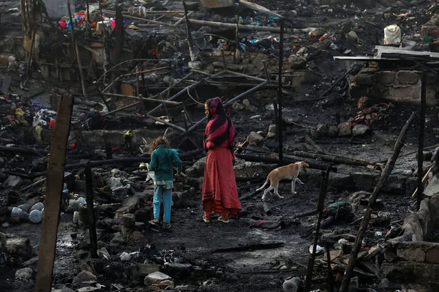 Siblings with their pet dog search for belongings as they visit the burnt-out house of their family after a fire broke out in a slum in Karachi, Pakistan on January 22, 2020. (Photo by Akhtar Soomro/Reuters)