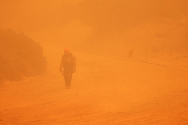 A hotshot firefighter walks through smoke as the Line Fire burns over 43,000 acres near Big Bear Lake in San Bernardino County, California, September 30, 2024. (Photo by David Swanson/AFP Photo)