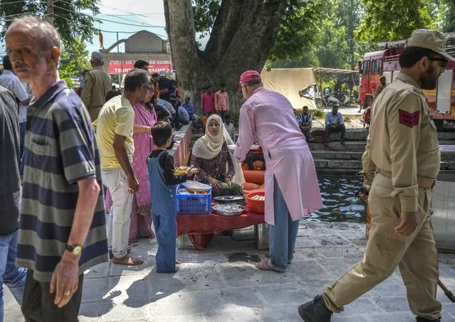 A Kashmiri Muslim woman, center, sells worship materials to Hindu devotees during the annual festival at the Kheer Bhawani Hindu temple in Tulla Mulla, outskirts of Srinagar, Indian controlled Kashmir, Wednesday, June 8, 2022. (Photo by Mukhtar Khan/AP Photo)