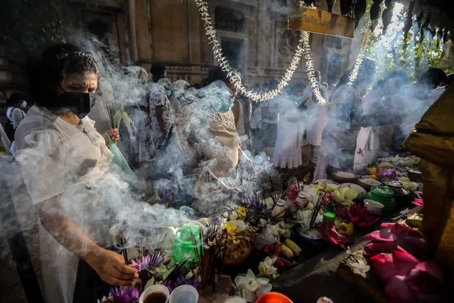 Sri Lankan Buddhist devotees offer flowers and incense sticks during a religious observance on the Poson full moon day at the Kelaniya Buddhist temple in Colombo, Sri Lanka, 14 June 2022. Poson full moon day commemorates the introduction of Buddhism to Sri Lanka in the 3rd century BC. Buddhism is the official religion of the South Asian island nation and the majority of the island's population traditionally engages in religious observances on full moon day. (Photo by Chamila Karunarathne/EPA/EFE)