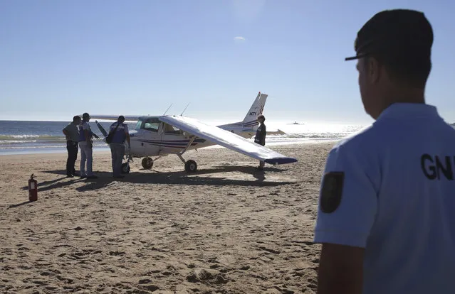 A policemen looks at coastguard officers check a small plane after an emergency landing on Sao Joao beach in Costa da Caparica, outside Lisbon, Wednesday, August 2, 2017. The light plane made an emergency landing on a packed beach near Lisbon on Wednesday afternoon, killing a 56-year-old man and an 8-year-old girl who were sunbathing, authorities said. (Photo by Armando Franca/AP Photo)