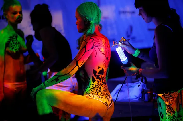 Artist use ultraviolet light paint on models during the World Bodypainting Festival in Poertschach, Austria, July 1, 2016. (Photo by Heinz-Peter Bader/Reuters)