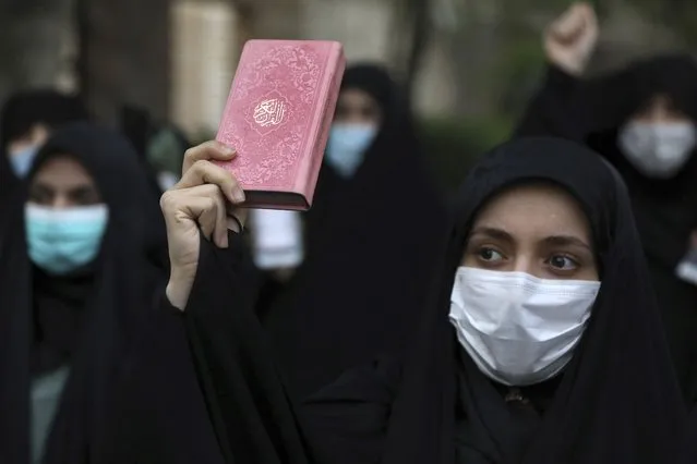A protester holds a copy of the Quran, the Muslims holy book, during a demonstration to condemn planned Quran burnings by a right-wing group in Sweden, in front of the Swedish Embassy in Tehran, Iran, Monday, April 18, 2022. Sweden has seen unrest, scuffles and violence since Thursday, triggered by Danish far-right politician Rasmus Paludan's meetings and planned Quran burnings across the country. (Photo by Vahid Salemi/AP Photo)