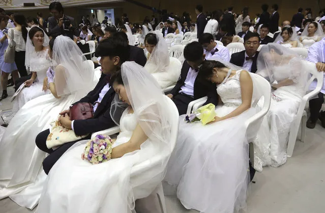 Brides takes a nap before a mass wedding ceremony at the Cheong Shim Peace World Center in Gapyeong, South Korea, Thursday, September 7, 2017. About 4,000 South Korean and foreign couples exchanged or reaffirmed marriage vows in the Unification Church's mass wedding arranged by Hak Ja Han Moon, wife of the late Rev. Sun Myung Moon, the controversial founder of the Unification Church. (Photo by Ahn Young-joon/AP Photo)