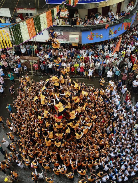 Indian youth form a human pyramid to break the “Dahi handi”, an earthen pot filled with curd, an integral part of celebrations to mark Janmashtami in Mumbai, India, Monday, August 18, 2014. (Photo by Rafiq Maqbool/AP Photo)