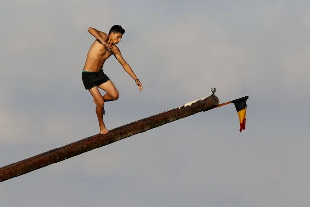 A competitor loses his balance on the “gostra”, a pole covered in grease, during the celebrations for the religious feast of St Julian, patron of the town of St Julian's, outside Valletta, August 30, 2015. (Photo by Darrin Zammit Lupi/Reuters)