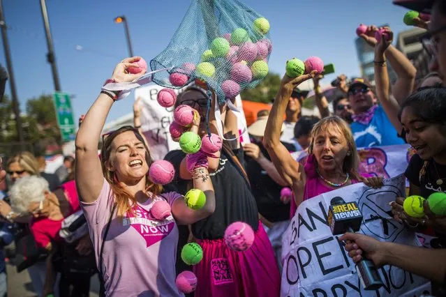 Anti-Trump activists and Code Pink members Alli McCracken (L) and Medea Benjamin (R) empty bags of tennis balls to highlight the fact that the balls are banned, while assault rifles are not, from the event zone surrounding the Republican National Convention, in downtown Cleveland, Ohio, USA, 19 July 2016. Numerous protest groups are expected to gather in Cleveland throughout the four-day-long convention. (Photo by Jim Lo Scalzo/EPA)