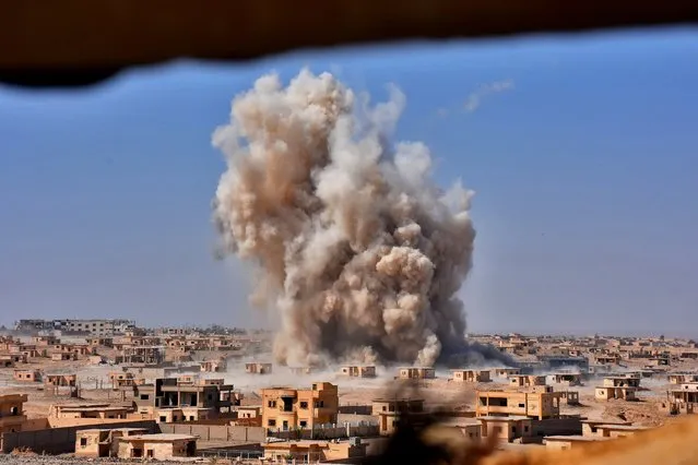 Smoke rises from buildings in the area of Bughayliyah, on the northern outskirts of Deir Ezzor on September 13, 2017, as Syrian forces advance during their ongoing battle against the Islamic State (IS) group. After breaking an Islamic State group blockade, Syria's army is seeking to encircle the remaining jihadist-held parts of Deir Ezzor city, a military source. (Photo by George Ourfalian/AFP Photo)