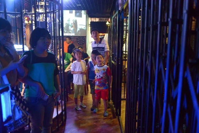 This picture taken on September 9, 2014 shows a family visiting a prison themed restaurant in Tianjin. (Photo by Wang Zhao/AFP Photo)