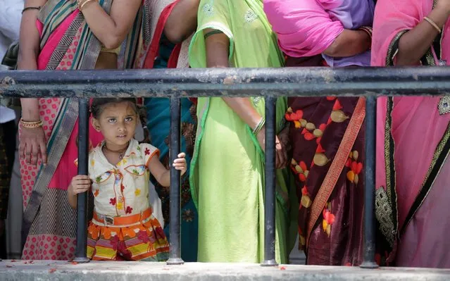 A child of a migrant labourer from Madhya Pradesh state stands in a queue with family members to board a bus to leave for the railway station to travel by a special train to Madhya Pradesh, during the ongoing lockdown, in Amritsar, India, 18 May 2020. The Indian government has arranged several special trains for migrant workers stuck in other states for their return to their native places. Indian authorities have announced to further extend the ongoing lockdown to stem the widespread of the SARS-CoV-2 coronavirus, until 31 May 2020. (Photo by Raminder Pal Singh/EPA/EFE/Rex Features/Shutterstock)
