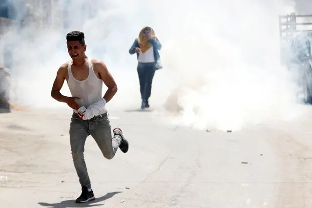 Palestinians run away from tear gas fired by Israeli forces during a raid after an Israeli soldier was killed by a rock, in Yabad near Jenin in the Israeli-occupied West Bank on May 12, 2020. (Photo by Mohamad Torokman/Reuters)