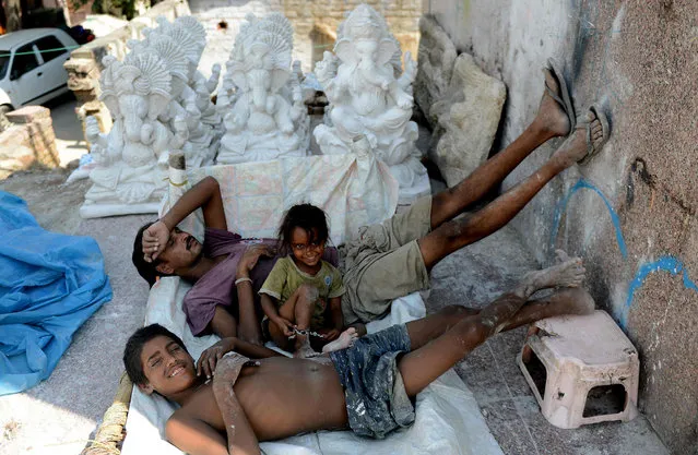 Indian workers take a nap near idols of the elephant-headed Hindu god Lord Ganesha at a roadside workshop in New Delhi on August 8, 2016. Hindu devotees bring home idols of Lord Ganesh in order to invoke his blessings for wisdom and prosperity during the 11-day long Ganesh Chaturthi festival which will cuminates with the immersion of the idols in water on September 6. (Photo by Money Sharma/AFP Photo)