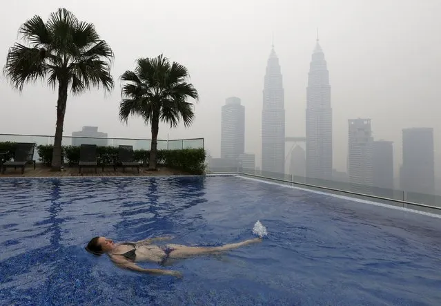 A woman swims in a rooftop pool in front of the Petronas Towers, shrouded by haze, in Kuala Lumpur, Malaysia, September 13, 2015. The so-called “haze”, caused by slash-and-burn clearances on the islands of Sumatra and Borneo, has pushed air quality to unhealthy levels in Malaysia and neighboring Singapore. (Photo by Olivia Harris/Reuters)