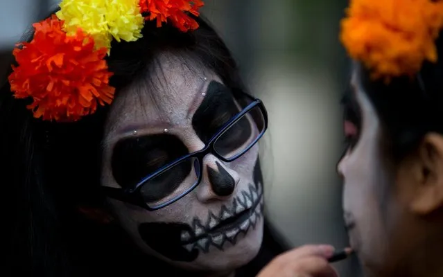 A woman paints the face of another participant before a Day of the Dead march calling for justice for victims of femicide, Mexico City, Wednesday, November 1, 2017. Mothers of women who were murdered led the march by more than 100 women wearing traditional “Catrina” face paint and carrying pictures of women who have been killed. (Photo by Rebecca Blackwell/AP Photo)